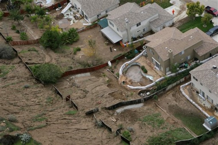 The backyards of homes along Autumn Chase Drive in Highland, Calif., are flooded with mud from the storm.
